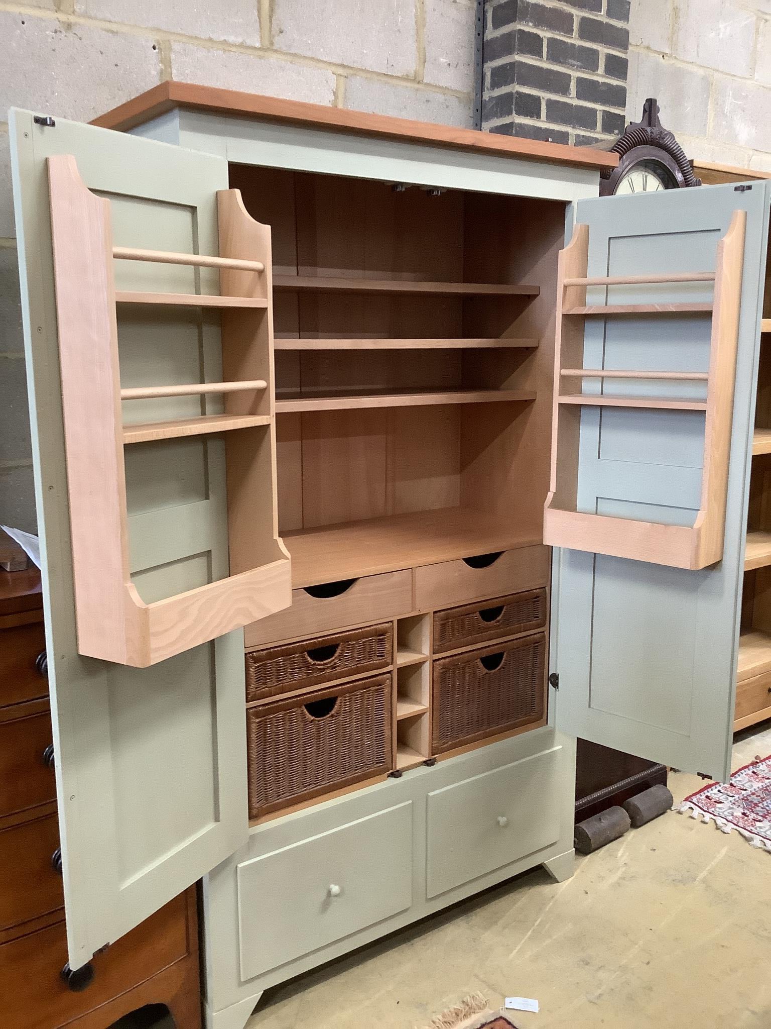 A modern light green painted kitchen cupboard, fitted shelves, racks, drawers and baskets, length 110cm, depth 51cm, height 183cm